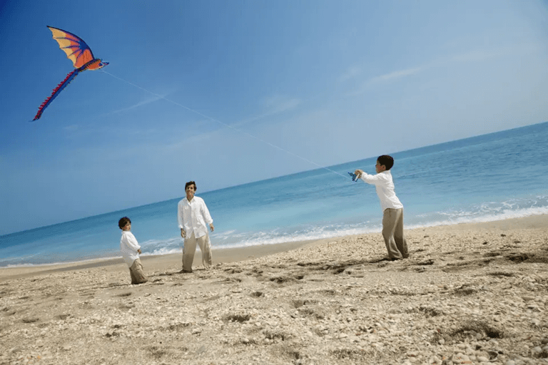 Family flying a kite on Caribbean beach during Easter in Grenada